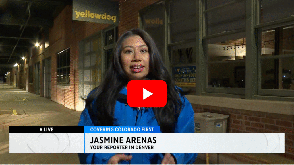 CBS Colorado reporter in blue jacket standing in front of YellowDog office, reporting on Period Positive Hygiene Drive